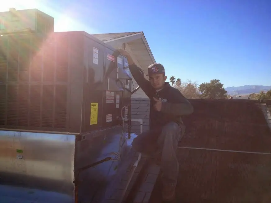 HVAC technician performing AC Tune-Up on a rooftop unit in Lake Grove